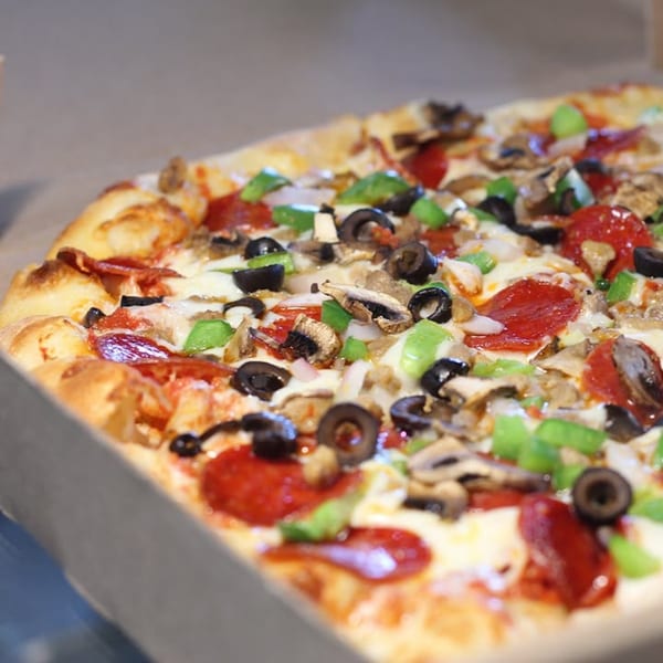 A Saruzzo's New York Pizzeria pizza with pepperoni, mushrooms, olives, and green peppers.