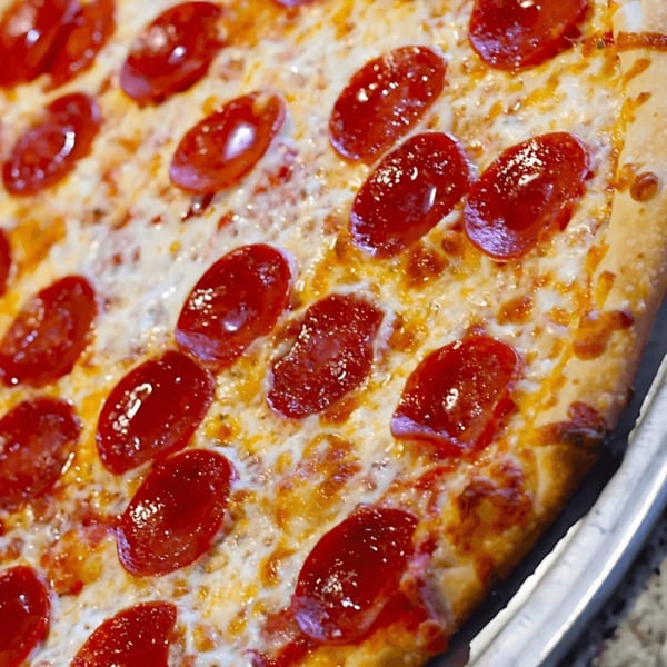 Close-up of a Saruzzo's New York Pizzeria pepperoni pizza with melted cheese and a golden crust.