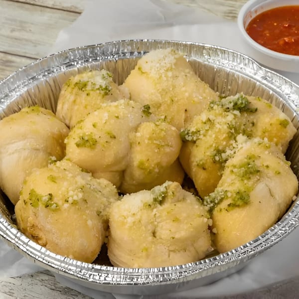 Garlic knots from Saruzzo's New York Pizzeria, topped with green herbs and parmesan cheese, with marinara.
